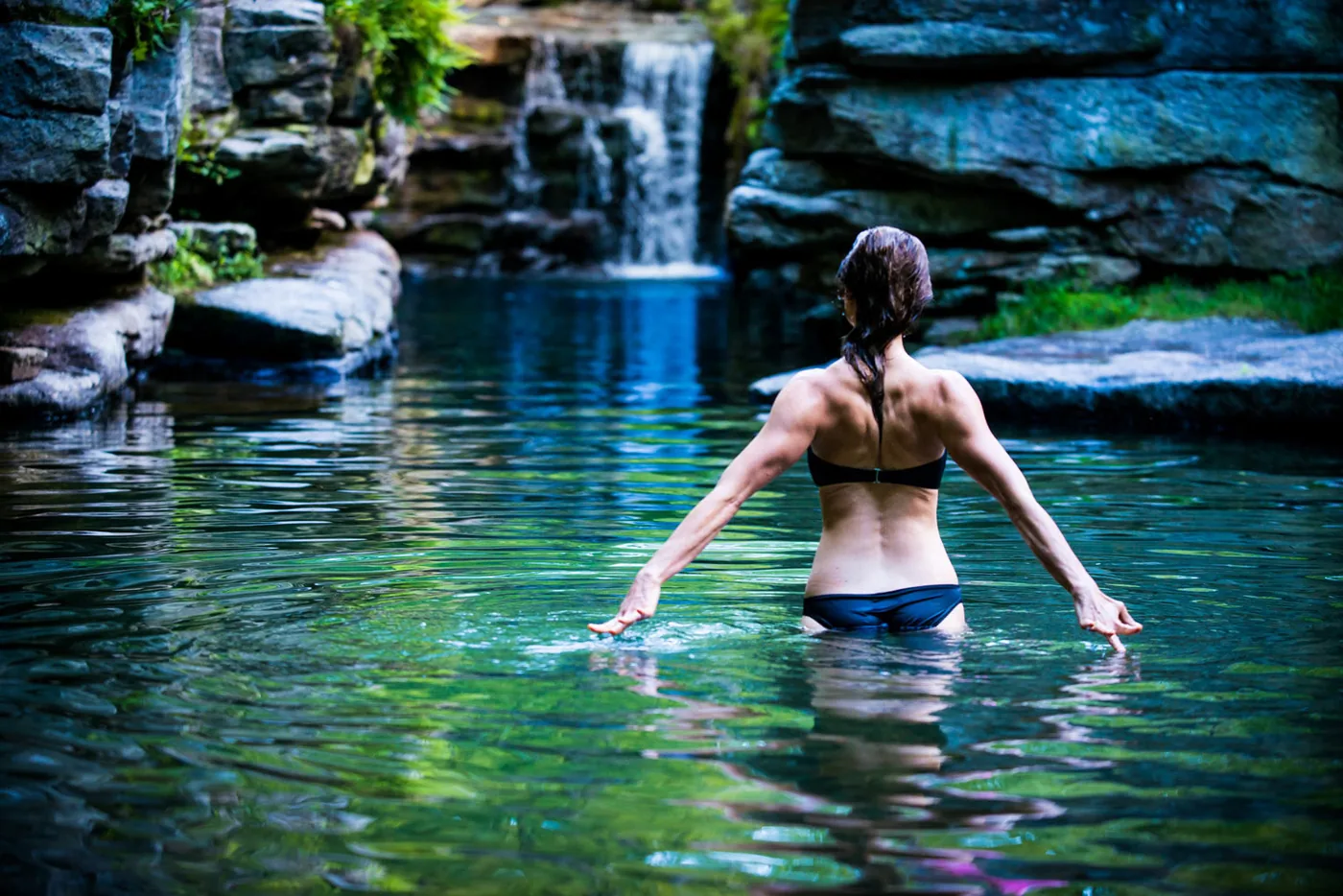 Woman entering a waterfall pool, photographed by Rob Gulotta